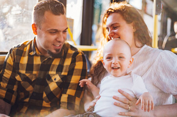 Parents riding a bus with their child during a day.