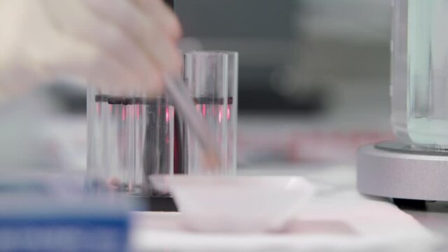 a tablet was thrown into a flask of water and dissolved by stirring water with a tablet. in the background flasks with leaves. close-up