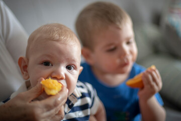 Hermanos comiendo naranja juntos mirando a la cámara