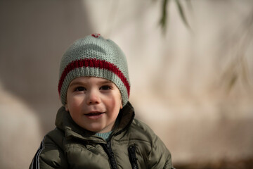 Niño bebé con gorro de lana sonriendo y mirando a la cámara