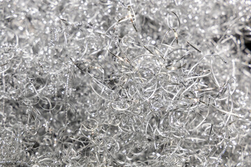 Aluminum shavings close up. Waste metalworking. Silvery metal shavings. Texture, wallpaper or background. Selected focus