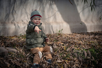 Niño jugando entre las hojas caídas de los árboles en otoño invierno