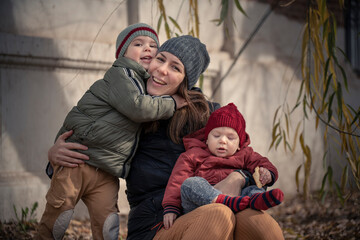 Mamá con sus hijos bebé y niño disfrutando del otoño invierno entre los árboles