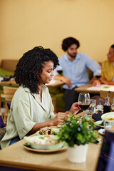 A Hispanic girl is sitting in a restaurant and having dinner.