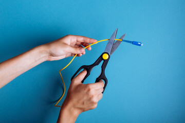 Destroy optical fiber with scissors. Isolated on blue