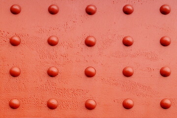 wall, red surface with raised dots forming a symmetrical pattern