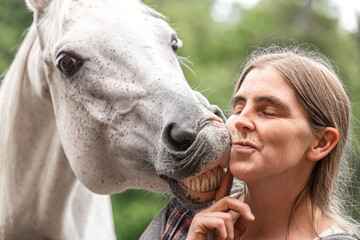 Funny equestrian team scene: A horse showing a kissing trick on command. Horse and owner having fun...