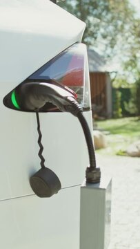 A electric car with a power cable connected to a charger stands in the backyard