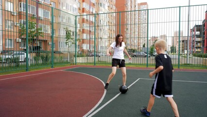 Mom and son are playing street soccer on a soccer field. Family training.