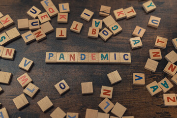 Symbolic depiction of the PANDEMIC with the use of colourful wooden letter puzzles creating that word. Post-covid world concept. Economy. High quality photo