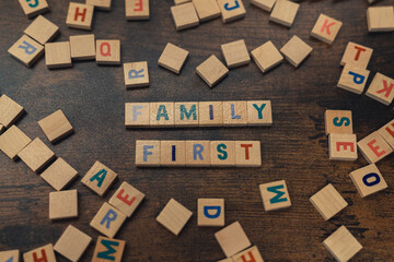 Family first. Strong message created by colorful wooden puzzles on a dark wooden background. Family concept. Prioritizing close people. High quality photo