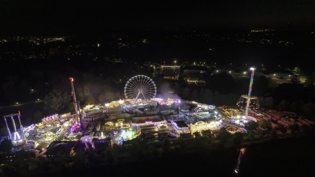 Colorful fair at night near river with city in the background aerial time lapse