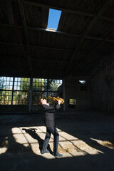 Fototapeta na wymiar Man playing jazz on saxophone in the abandoned factory building on a sunny summer day
