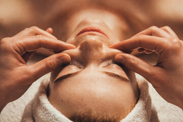 Beautician massaging face of caucasian woman in spa salon. Young woman enjoying massage at spa...
