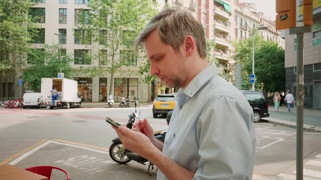 Young man tourist using smartphone close-up, businessman writing message in phone, standing in street. Guy chatting with friends online, surfing the internet. 