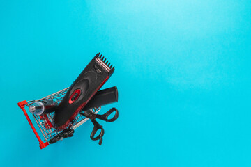 Men's haircut machine, scissors and comb lie in a mini cart on a blue background