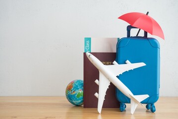 Red umbrella cover airplane, passport, flight tickets and suitcases travelers on wooden background....