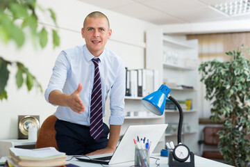 Fototapeta premium Portrait of positive businessman meeting partners at company office, giving hand