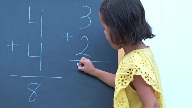 girl doing a sum on a blackboard preparing to go back to school