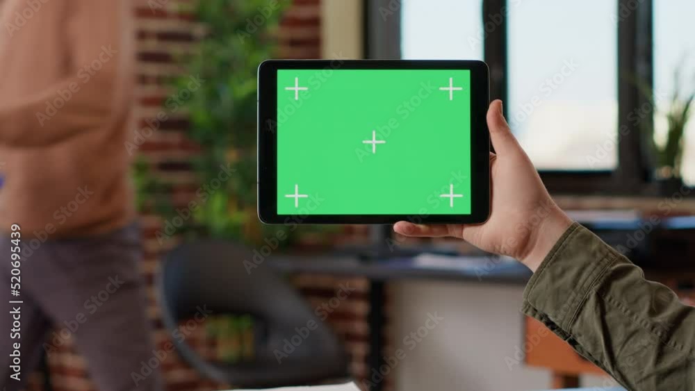 Poster male freelancer holding horizontal greenscreen on digital gadget, using tablet with blank mockup tem