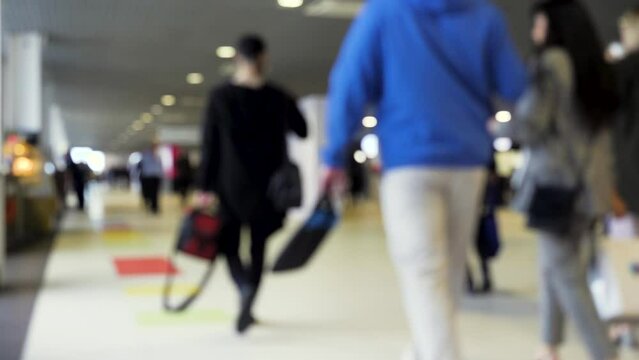 Exhibition hall. Media.A huge stream of people walking with bags filmed without focus