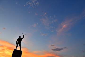 夕日に赤く染まる空と湘南海岸に立つ平和像