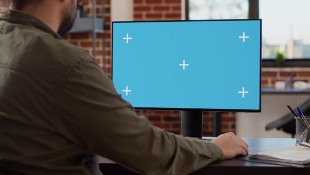 Company manager looking at computer with greenscreen to work on startup business, using blank chroma key display. Working with isolated mockup copyspace on monitor background at desk.