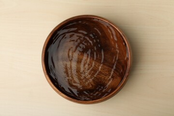 Bowl full of water on wooden table, top view