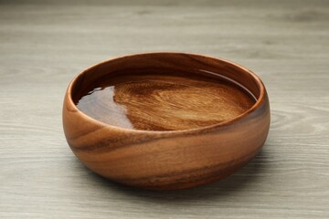 Bowl with water on wooden table, closeup