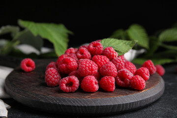 Wooden board with fresh ripe raspberries on table, closeup