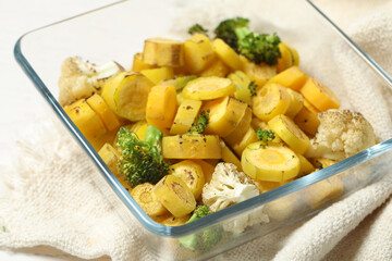 Baked yellow carrot with broccoli and cauliflowers in glass dish on table, closeup