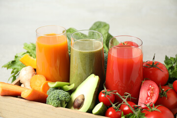 Delicious vegetable juices and fresh ingredients on light background