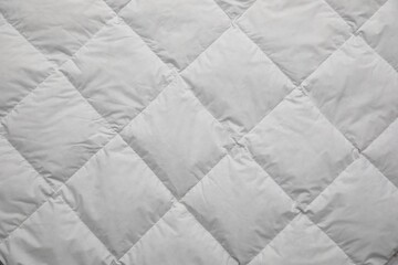 Soft quilted blanket as background, top view
