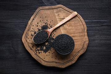 Board with black sesame seeds on wooden table, top view