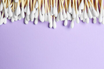 Many cotton buds on violet background, flat lay. Space for text