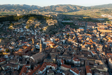Picturesque drone view of Calatayud cityscape in spring in valley of Iberian mountain area overlooking brownish tiled roofs of residential buildings, Spain