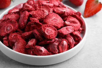 Freeze dried and fresh strawberries on light grey table, closeup