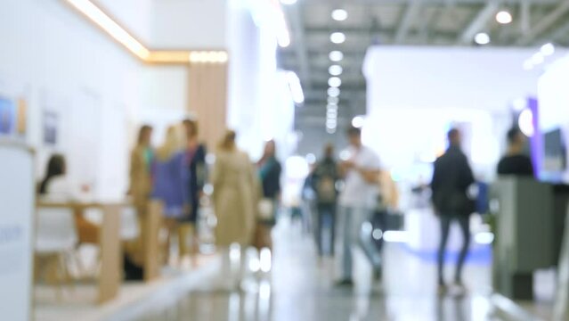 Defocused crowd at the exhibition center. Media. Blurred background with walking people inside the building.