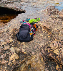 Backpack and sneakers on conglomerate sedimentary rock