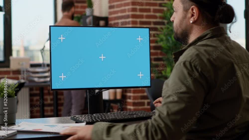 Poster startup employee looking at greenscreen template on monitor, working in business office with blank c