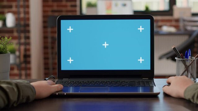POV of male freelancer using laptop with greenscreen at office desk, working with blank mockup template on wireless pc. Looking at isolated chroma key display with copyspace background.