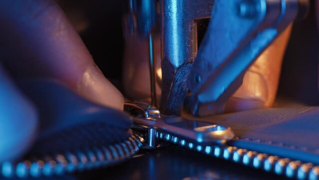 The leather craftsman produces leather products on sewing machine.Close-up of the sewing machine needle moves up and down rapidly. Tailor sews black leather fabric in sewing workshop.4K