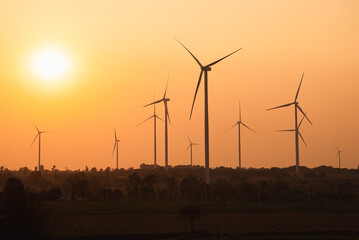 Windmills for electric power production, windmill farm or wind park with high wind turbines for generation electricity at sunset. Green energy concept.