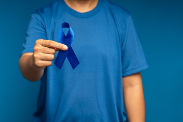 A male hand is holding a blue ribbon while standing on a blue background