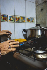 Beautiful hands of elderly latino woman cooking on traditional kitchen stove with gas burners with traditional toaster with 'sopaipillas' (fried pastry) and pots