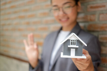 Home insurance concept and real estate. Businesswoman holding a house model working in investment about renting a house, buying a house, and home insurance