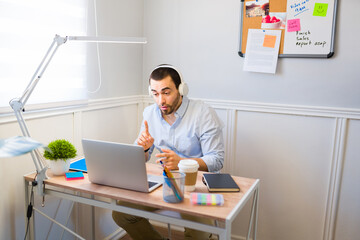 Naklejka premium Caucasian man with headphones talking during a work video call at home