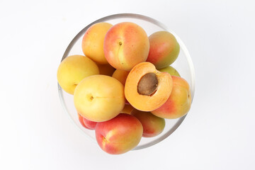 Fresh ripe juicy yellow orange red apricot fruit pile whole cut half slice seed in transparent glass bowl on white background flat lay top view