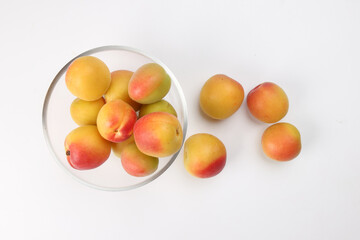 Fresh ripe juicy yellow orange red apricot fruit pile whole cut half slice seed in transparent glass bowl on white background flat lay top view