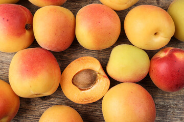 Fresh ripe juicy yellow orange red apricot fruit pile whole cut half slice seed on rustic wood background flat lay top view border frame copy text space